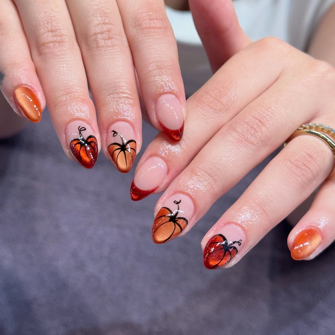 Warm orange and nude almond nails with small pumpkin and spider accents