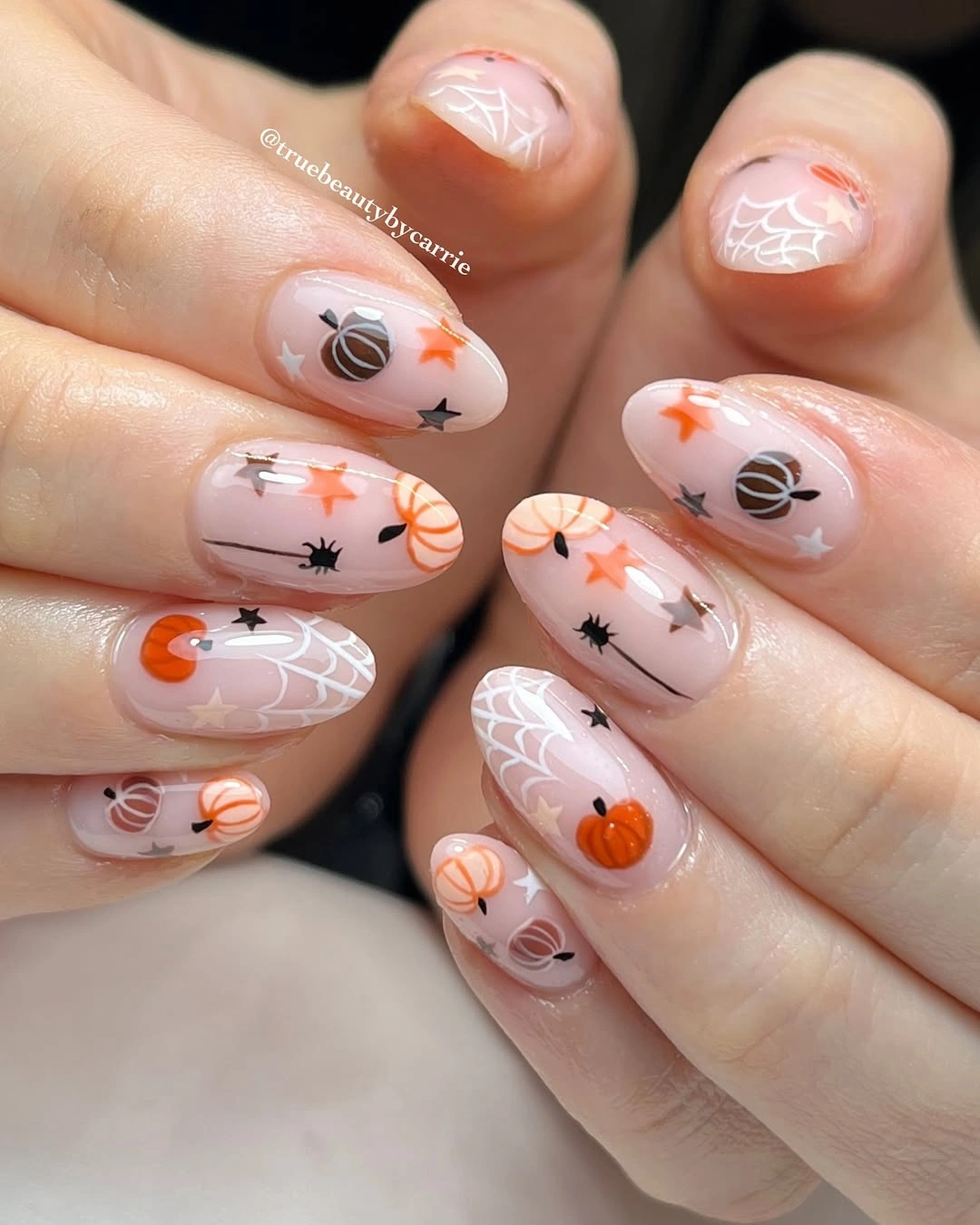 Short milky nude nails with tiny pumpkins, ghosts, stars, spiders, and web lines