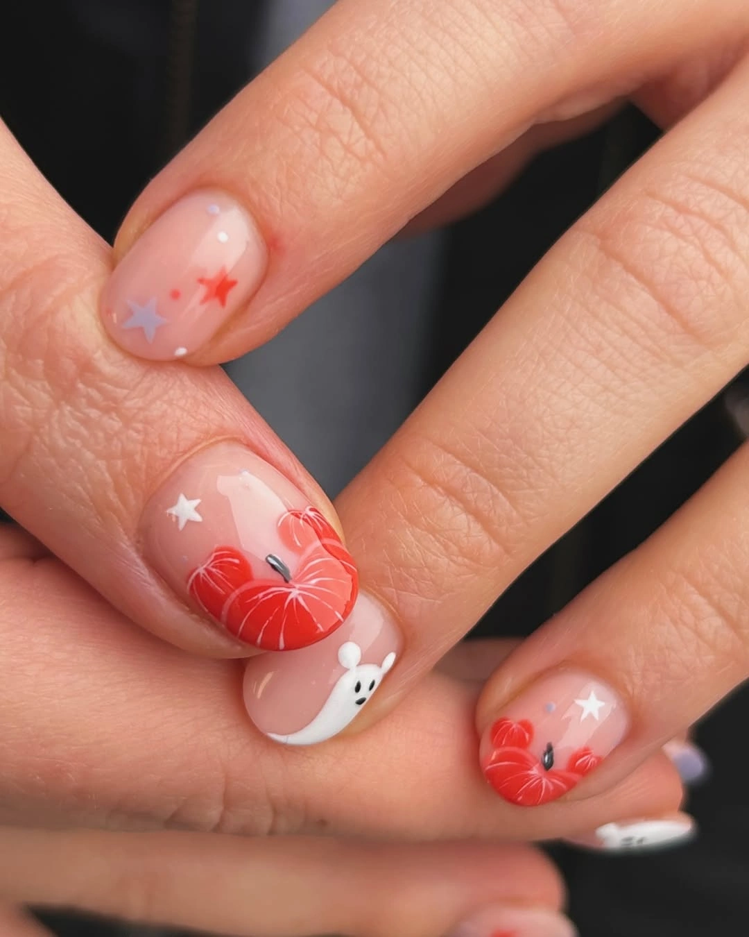 Short nude nails with orange pumpkin, white ghost, stars, and fine black details