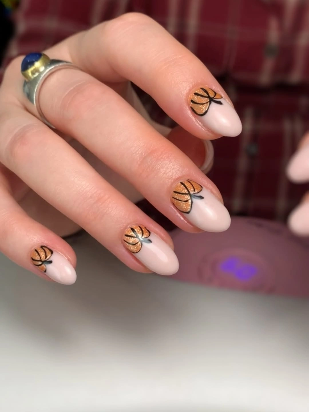 Short soft nude nails with petite black line motifs and restrained gold detail