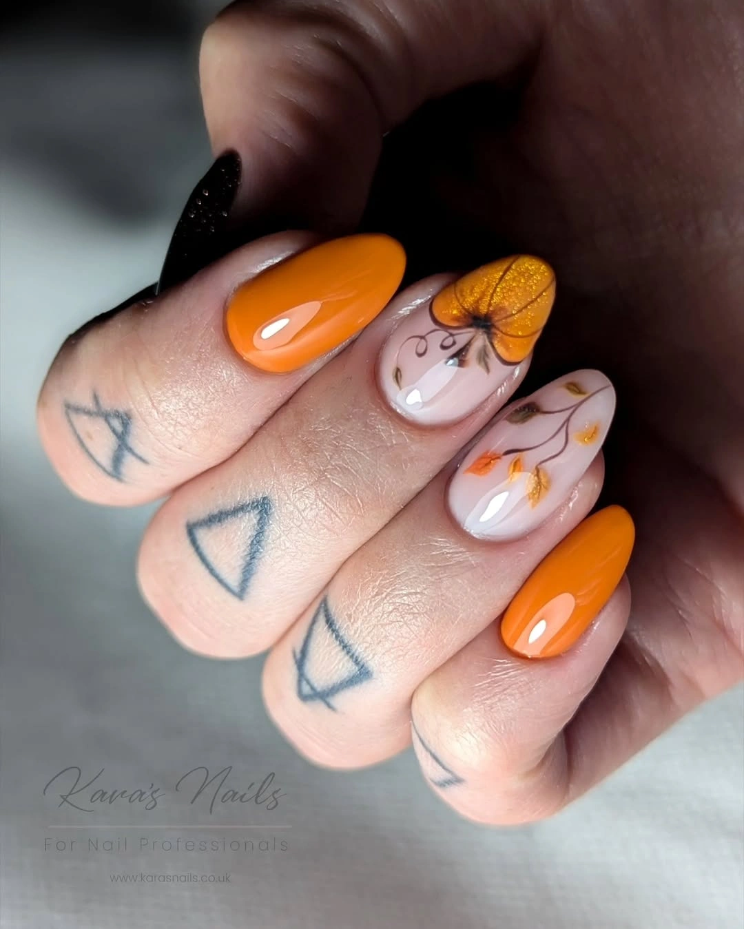 Medium almond nails in orange and yellow with white ghosts and pumpkin accents
