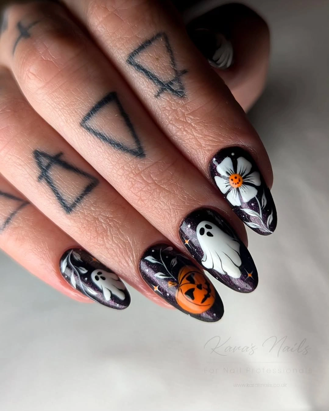 Glossy black almond nails with a white ghost and orange pumpkin accents