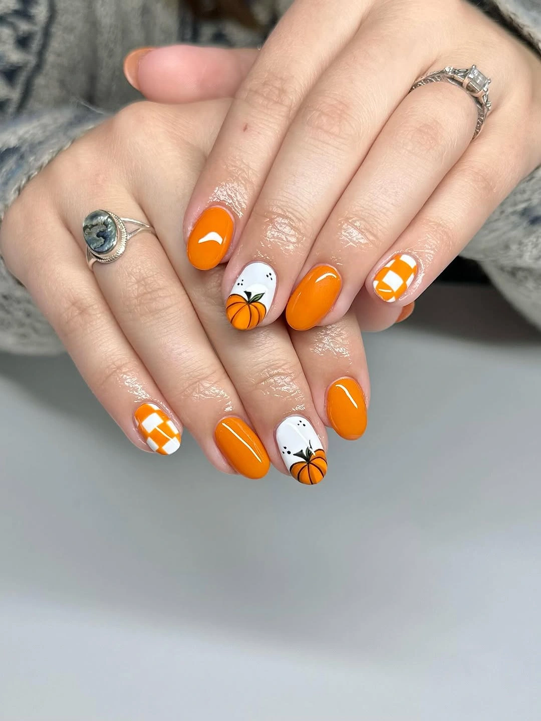 Short orange nails with white pumpkin and candy-corn inspired accent details