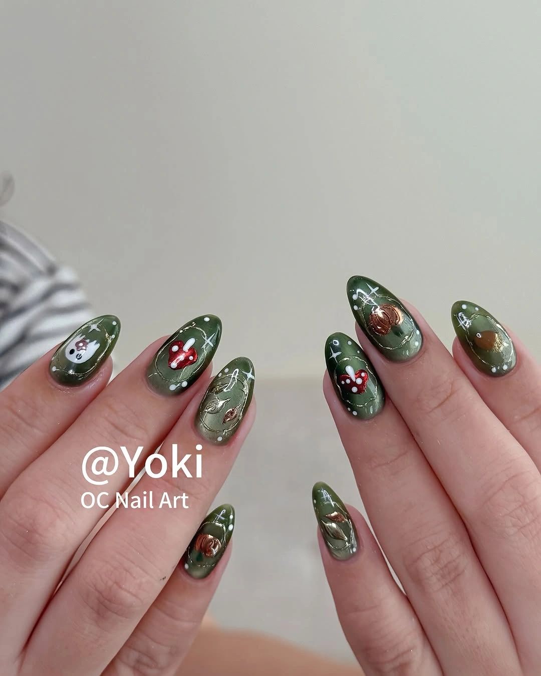 Deep green almond nails with small red, white, and brown Halloween accents