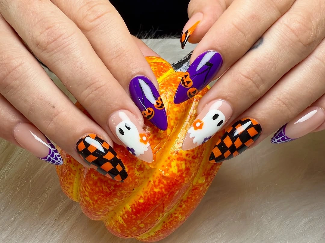 Long pointed Halloween nails with purple checkerboard, ghosts, pumpkins, and eye accents