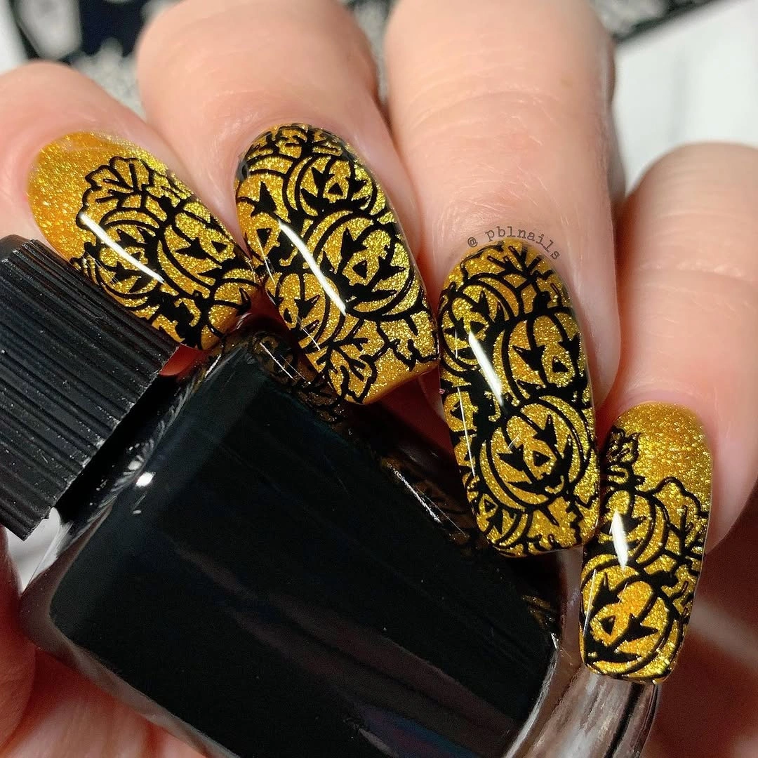 Long almond nails with gold glitter and black ornate patterns
