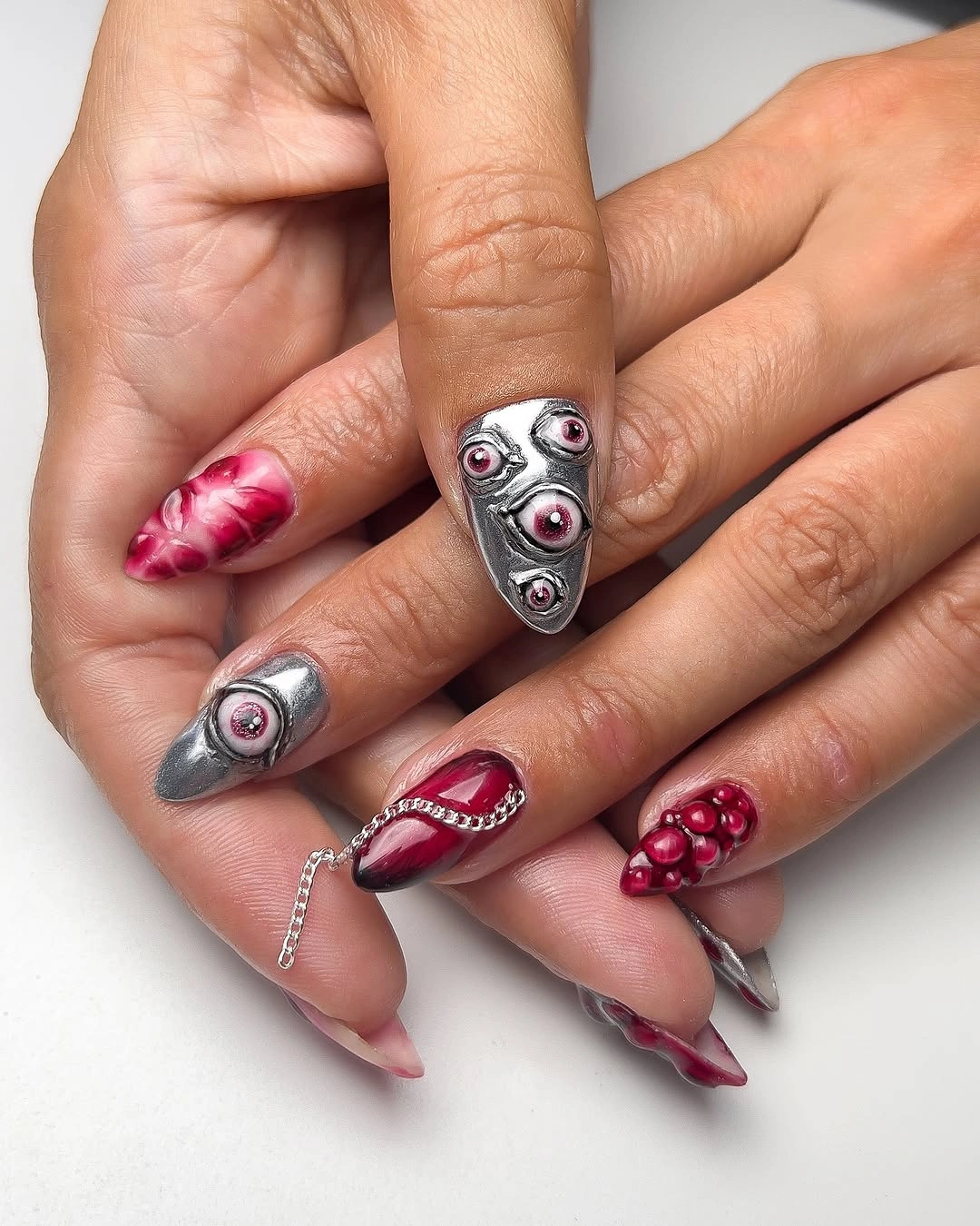 Long pointed nails with silver eye details and red accents