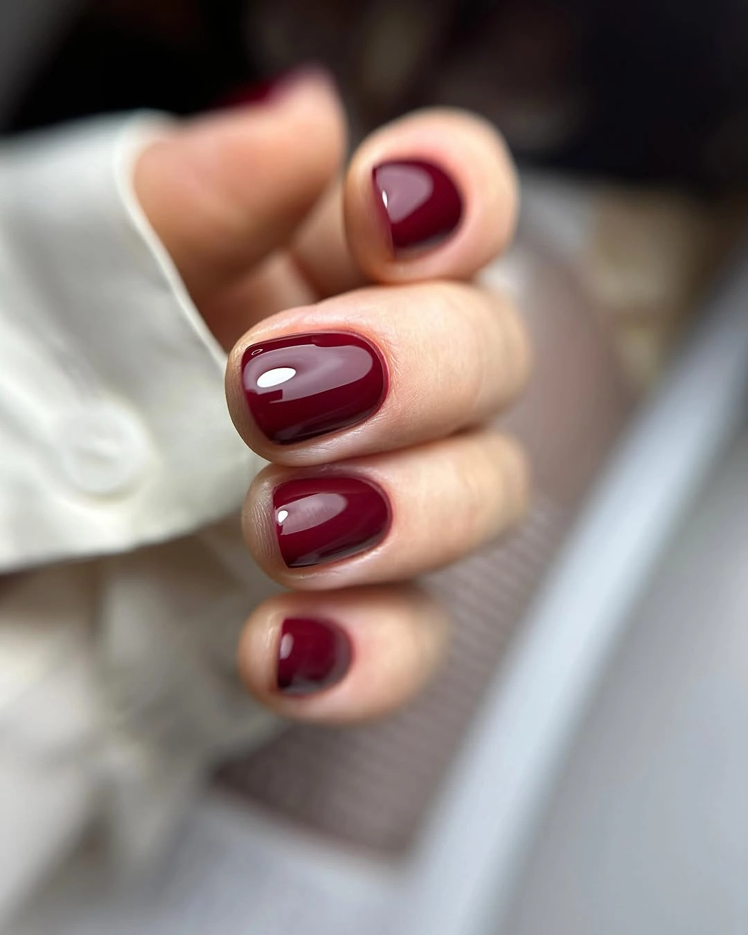 Short rounded glossy nails in a warm rich maroon shade
