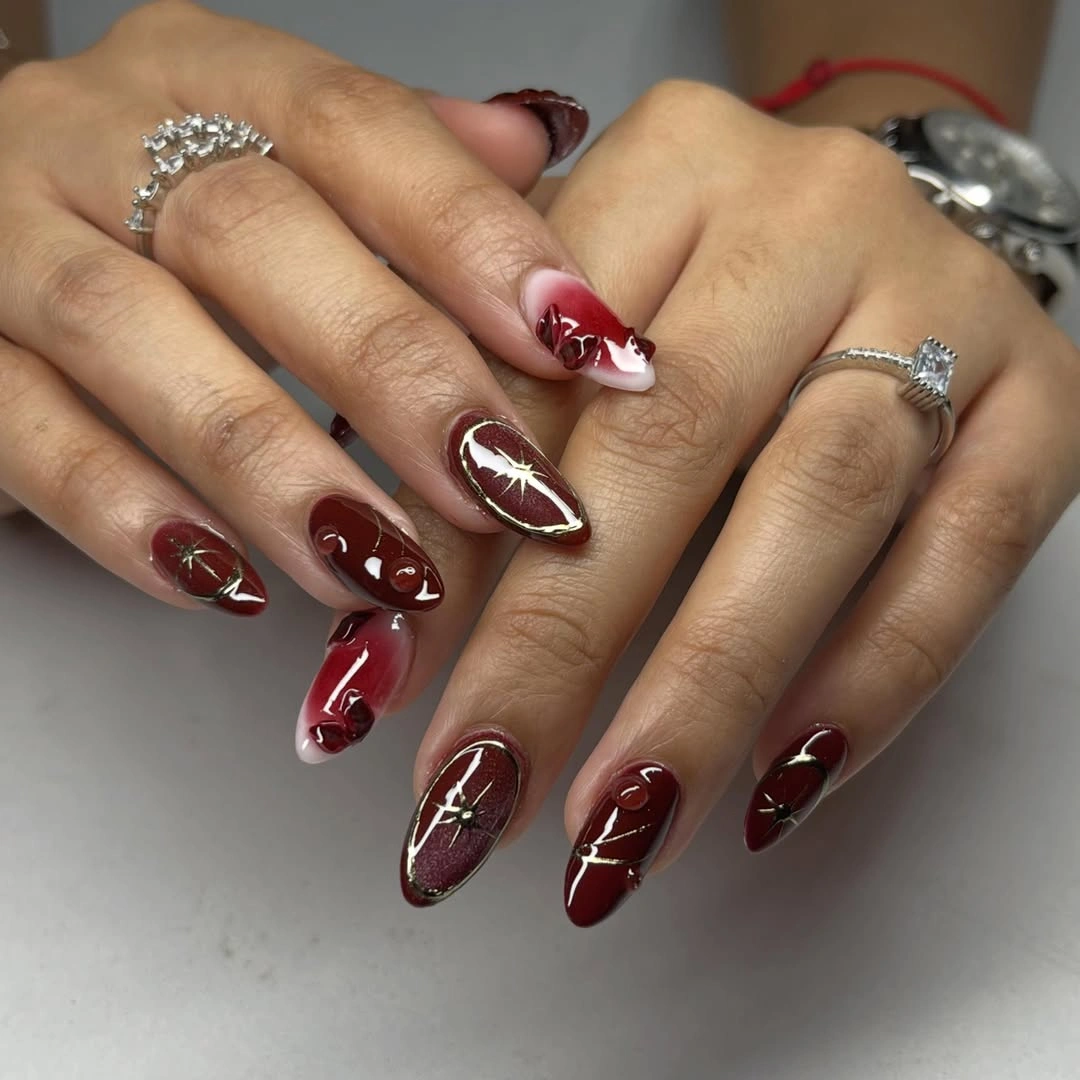 Long dark wine almond nails with fine pale botanical linework and swirls