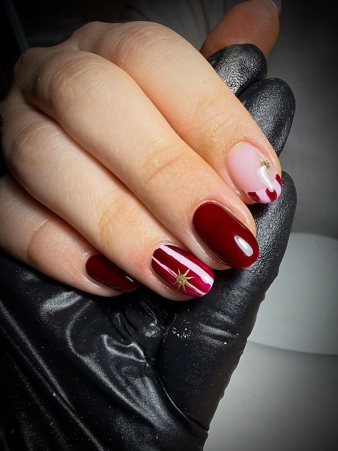 Short deep burgundy nails with bright white and red starburst accent details