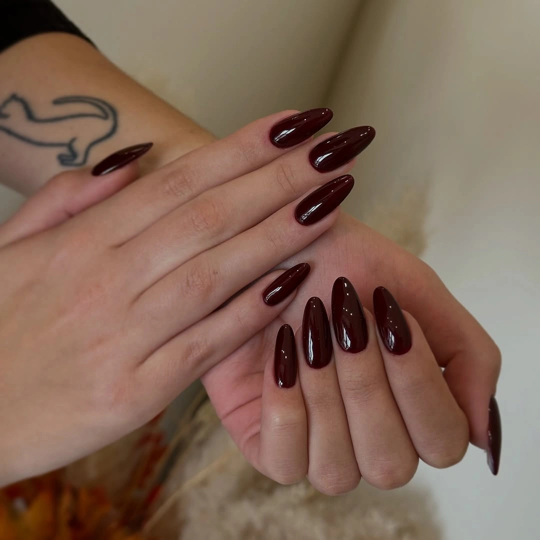 Long glossy almond nails in a very dark chocolate-maroon shade