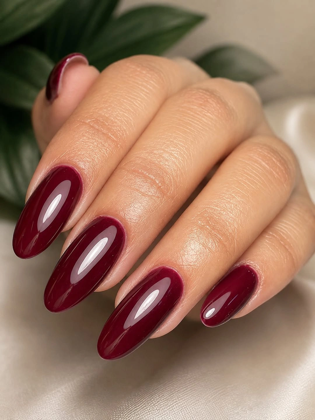 Medium-long glossy burgundy almond nails with soft centered highlights
