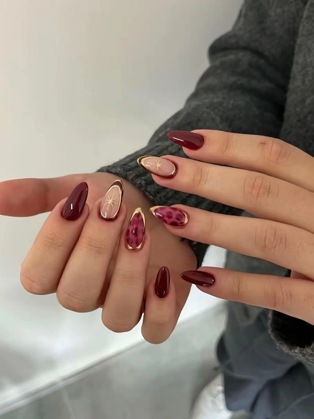 Mixed burgundy nails with nude gold star details and berry abstract accents