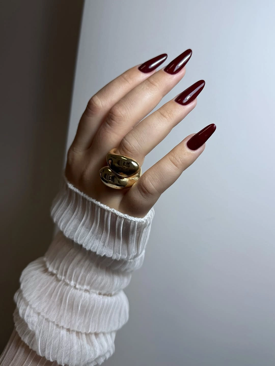 Long pointed burgundy nails with clean uniform glossy color
