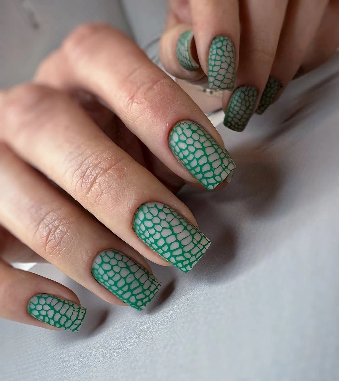 Neutral square nails with open irregular green outlined web-like pattern