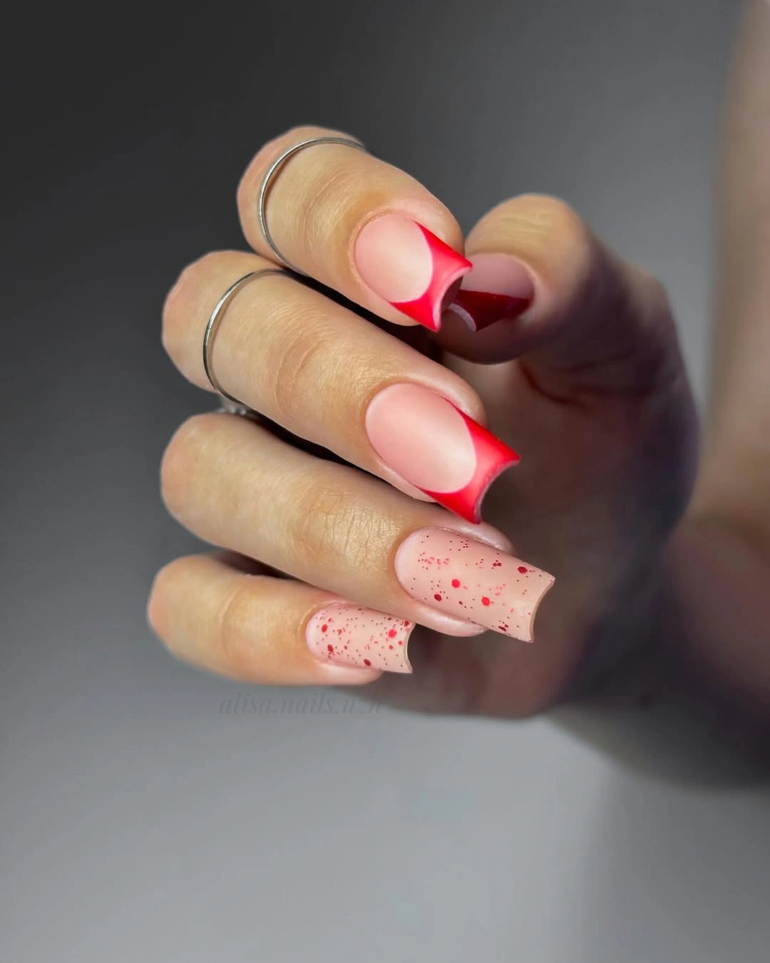 Sheer pink square nails with sharp bright red angled French edges and dots