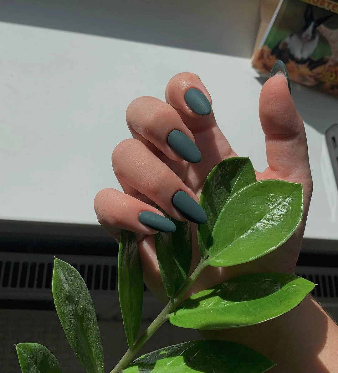 Muted forest green medium almond nails with a smooth matte finish