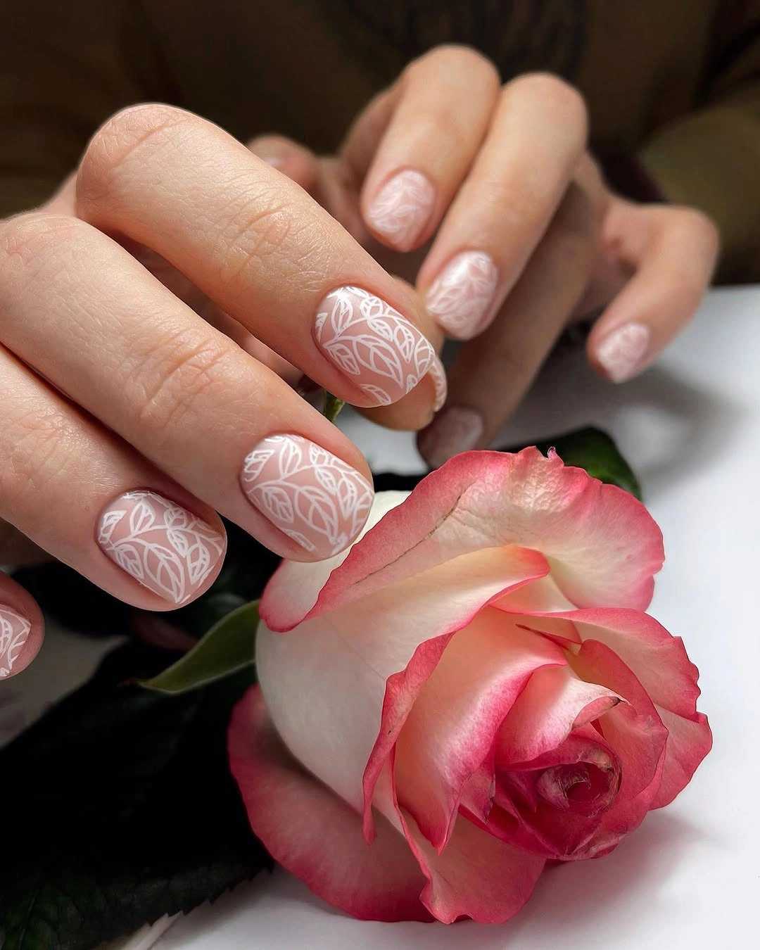 Pale blush short nails with delicate white leaf-like line pattern