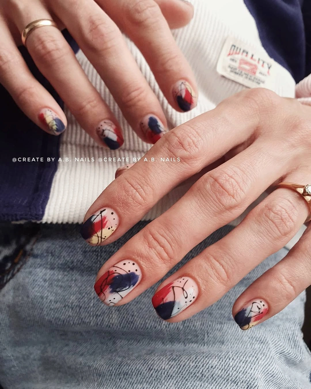 Cream short nails with navy burgundy and black abstract curved accents