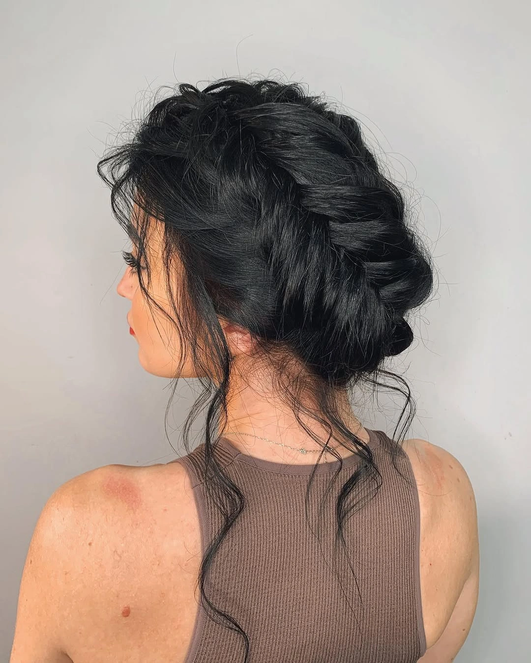 textured low updo with loose strands at the nape