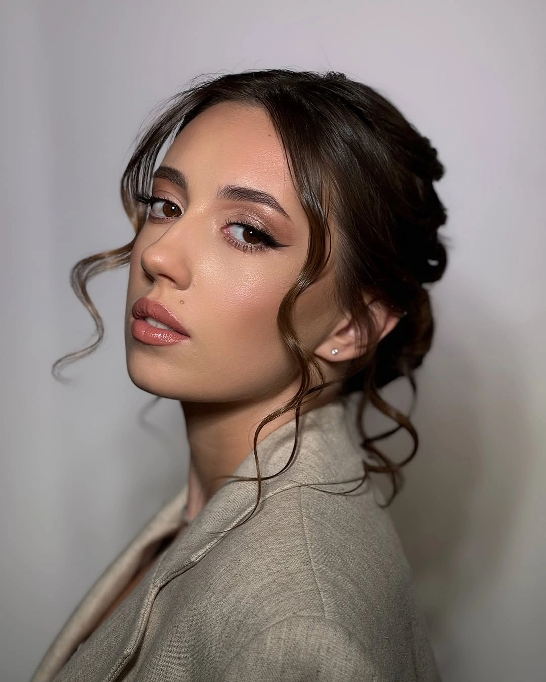 low brunette updo with two loose face framing tendrils