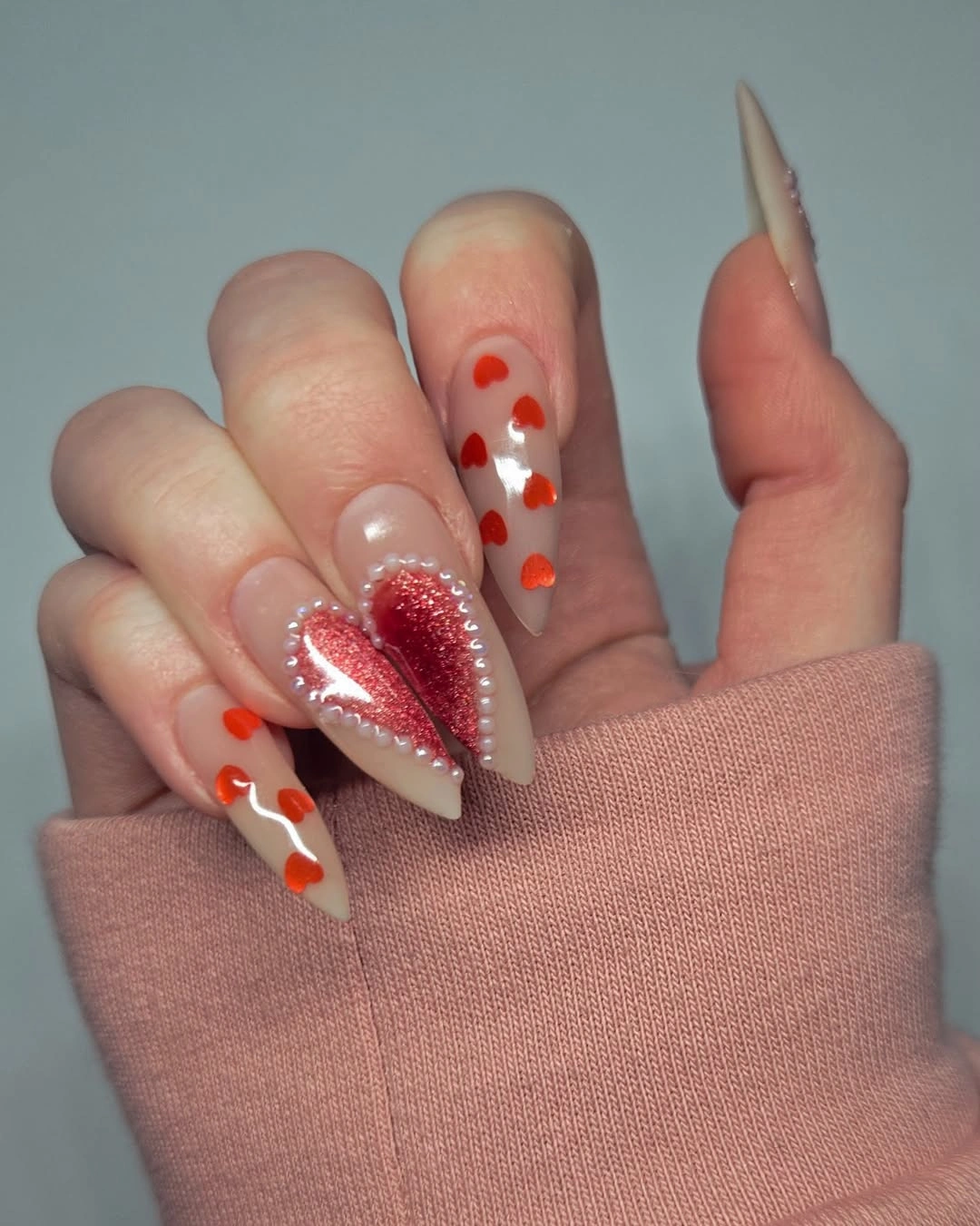 Long pale pointed nails with red hearts