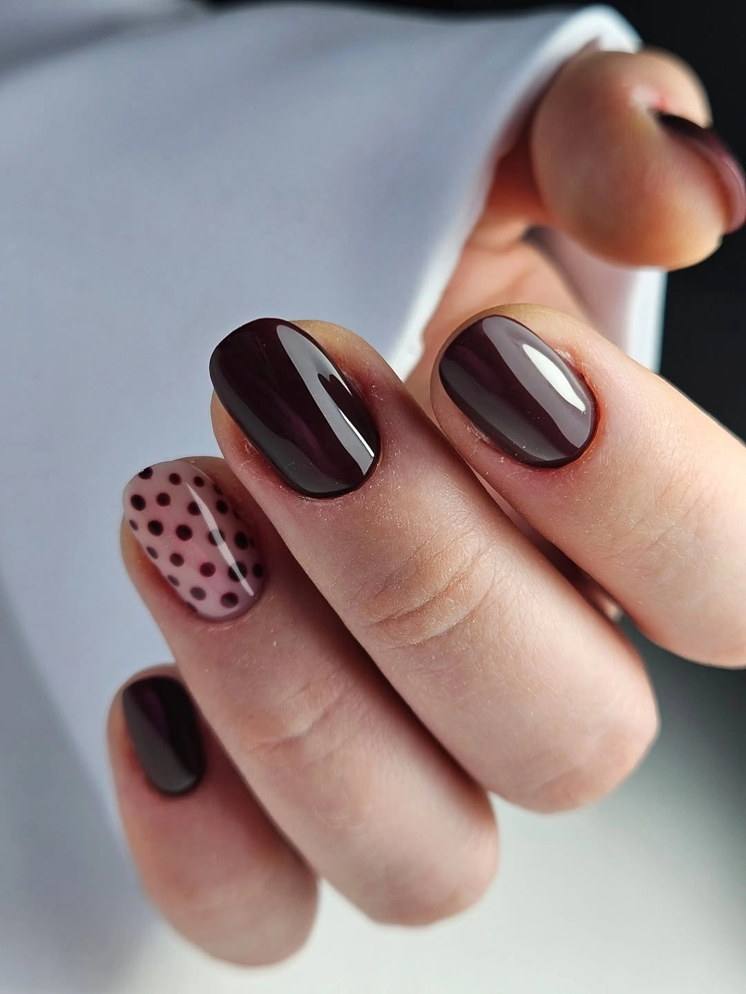 Short chocolate nails with one pale pink black polka-dot accent nail