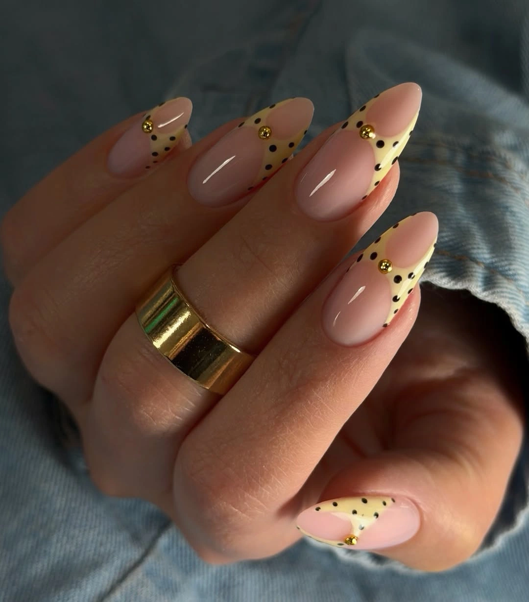 Long nude almond nails with pale yellow dotted tips and tiny gold details