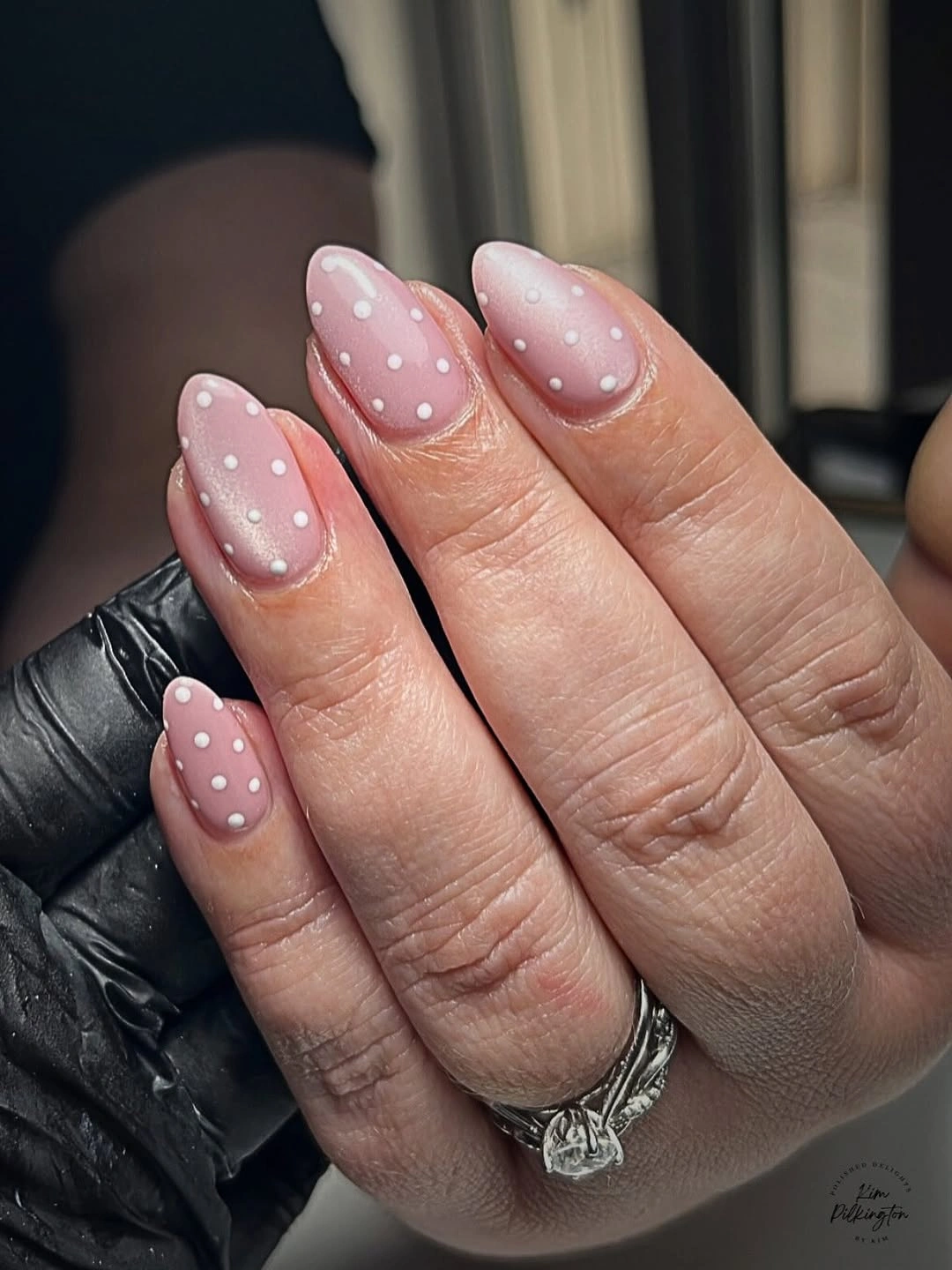 Sheer pink almond nails with scattered small white polka dots