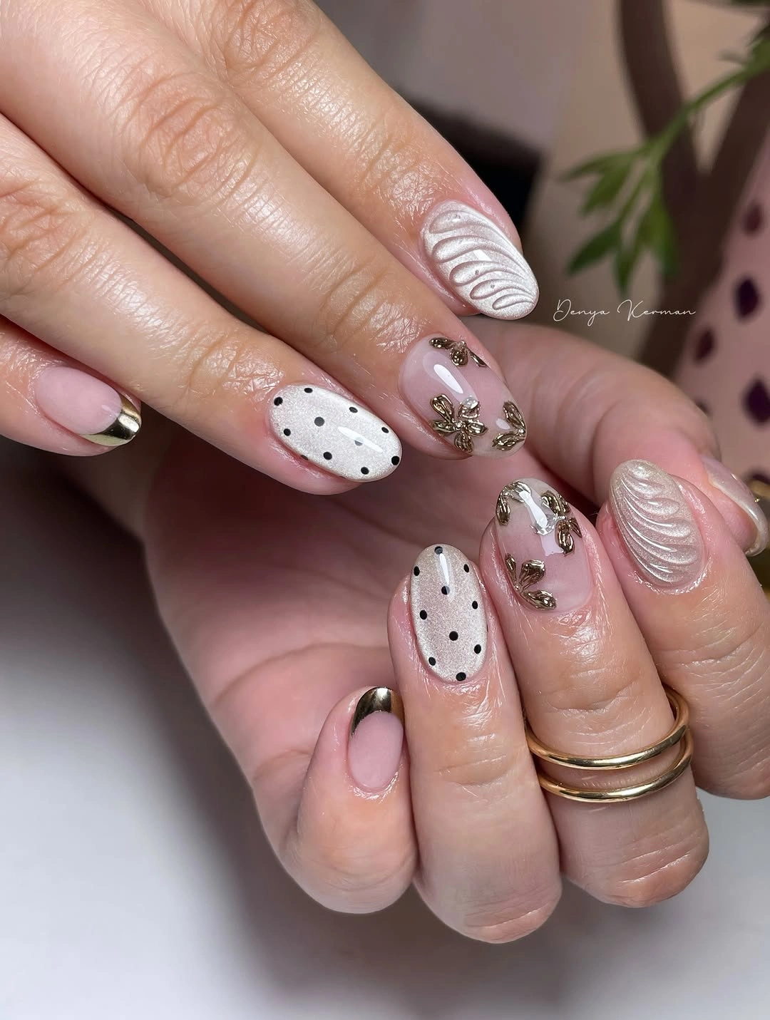 Pale pink nails with black dots and light textured-looking floral accents
