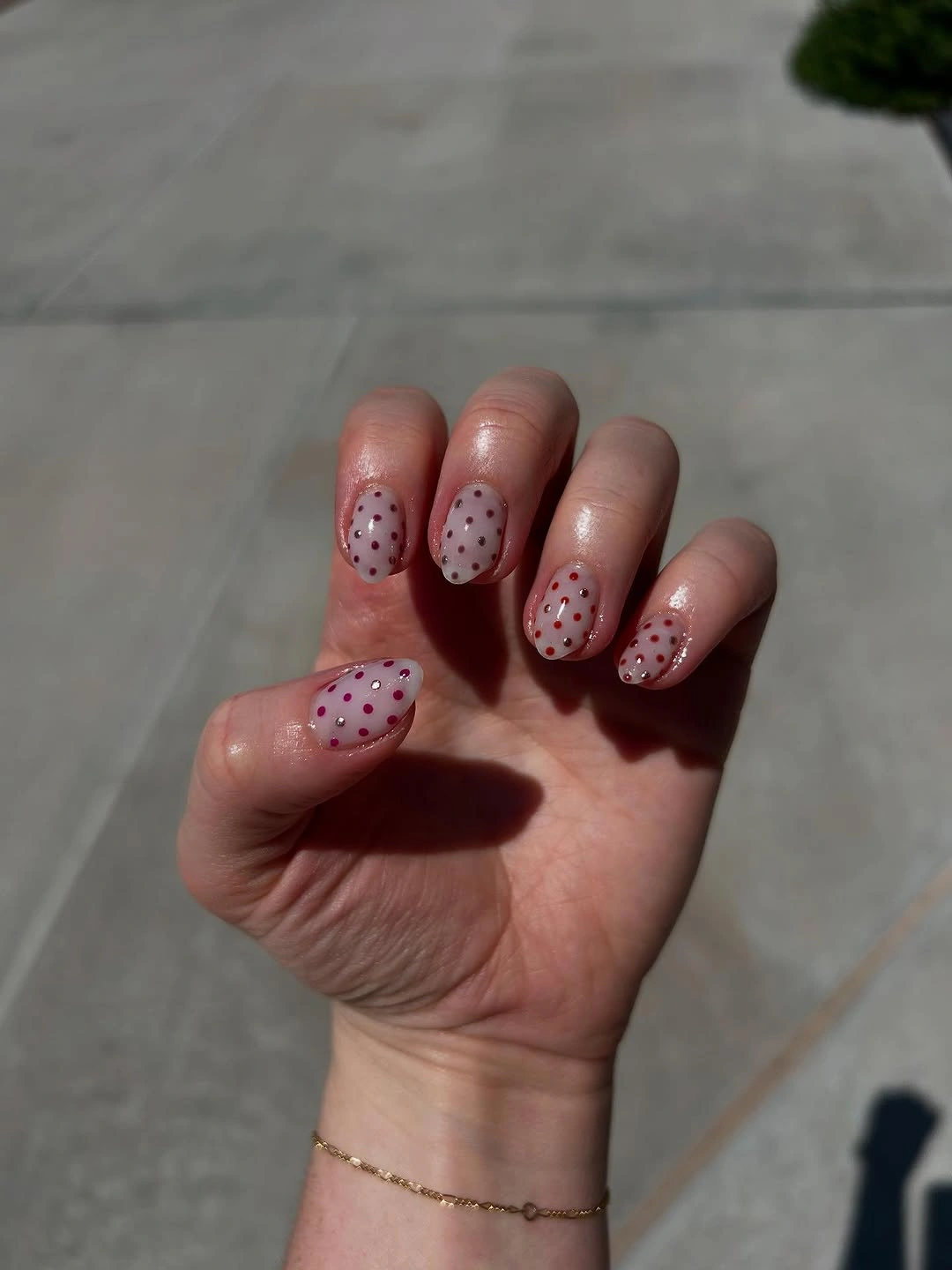 Sheer blush nails with tiny scattered multicolor polka-dot details