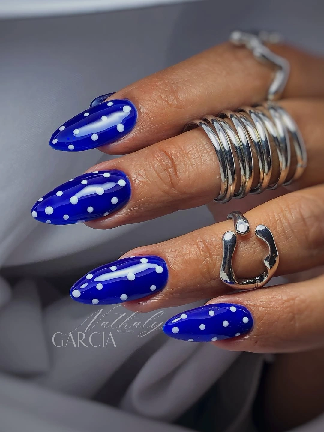 Cobalt blue almond nails with crisp medium white polka dots
