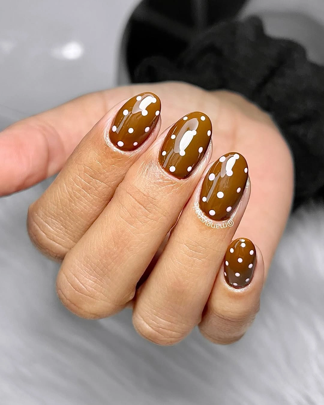 Short caramel brown rounded nails with white polka dots and small bow details