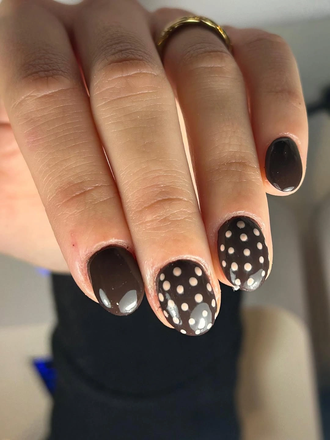 Short glossy black nails with soft cream polka-dot accent details