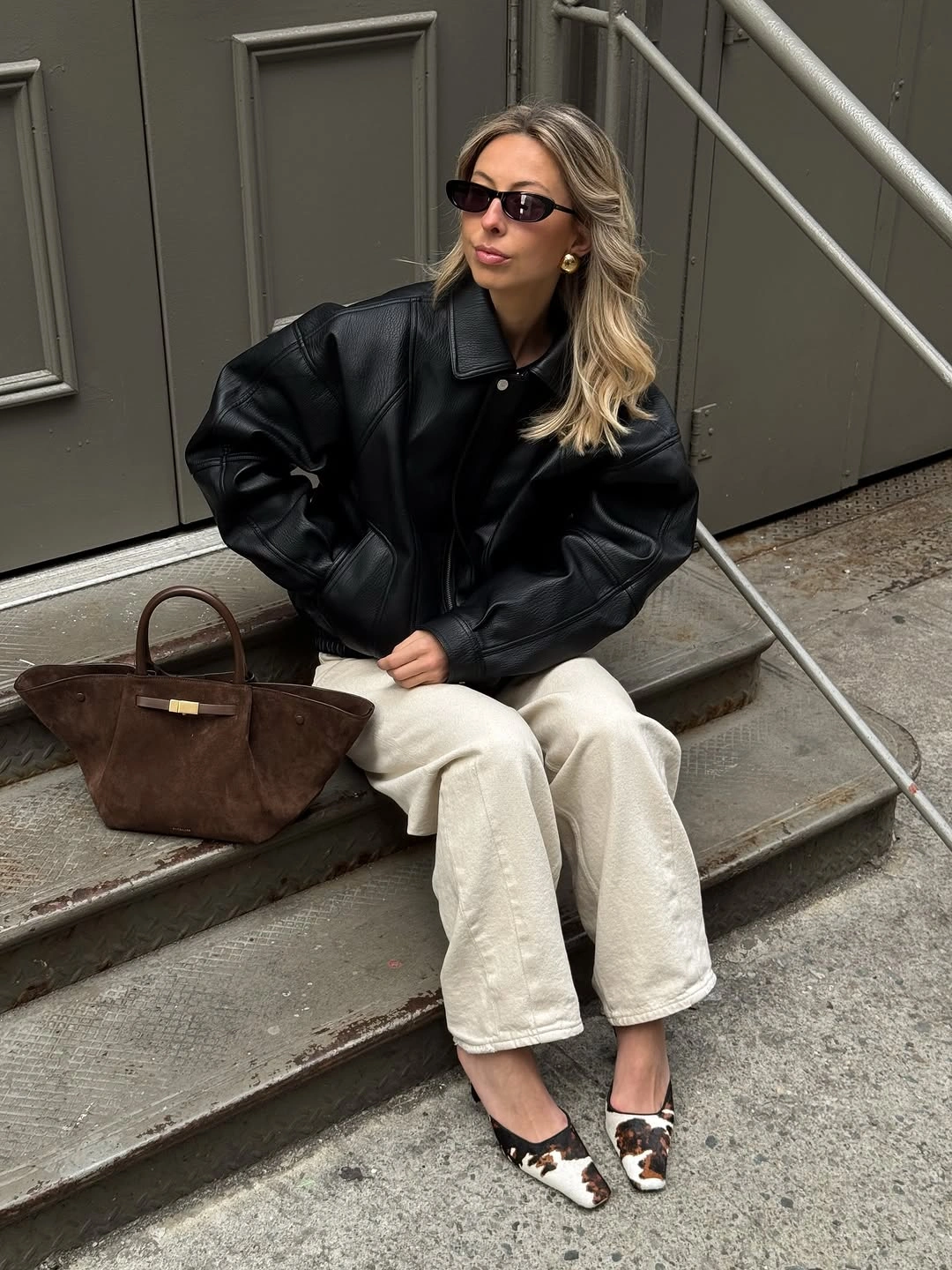 Black jacket with cream jeans, two-tone shoes, and brown tote