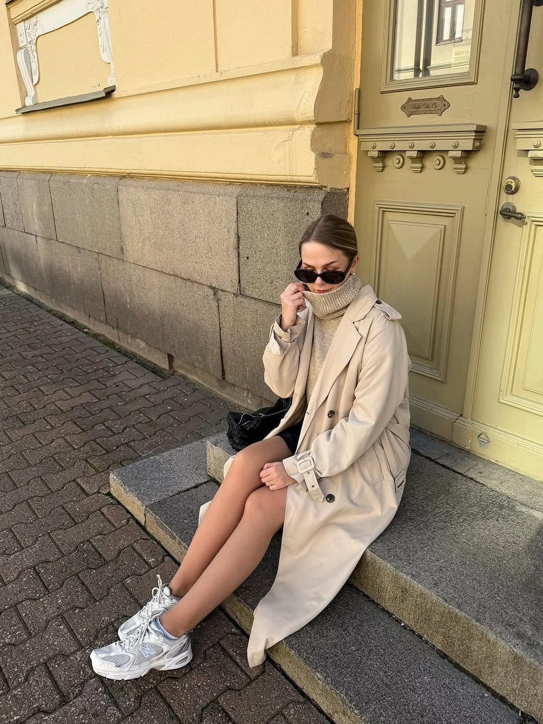 Beige trench over dark short base with pale scarf and sneakers