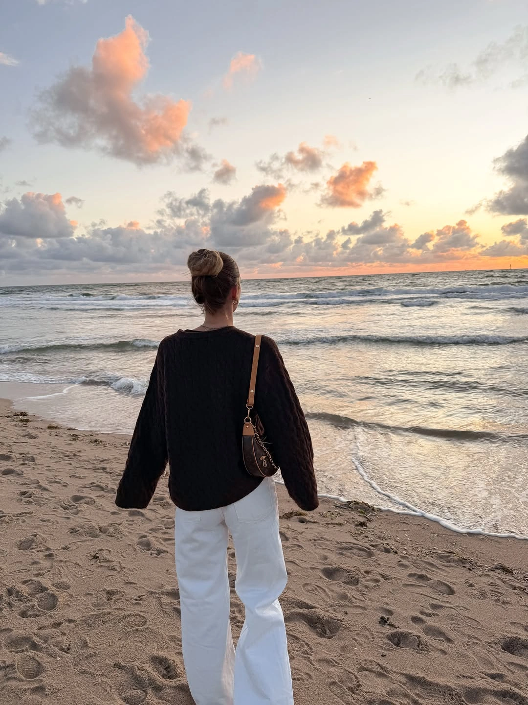 Oversized black knit with white wide-leg trousers and brown bag