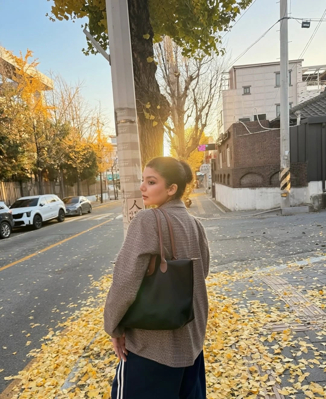 Tan collar jacket with white turtleneck and dark trousers