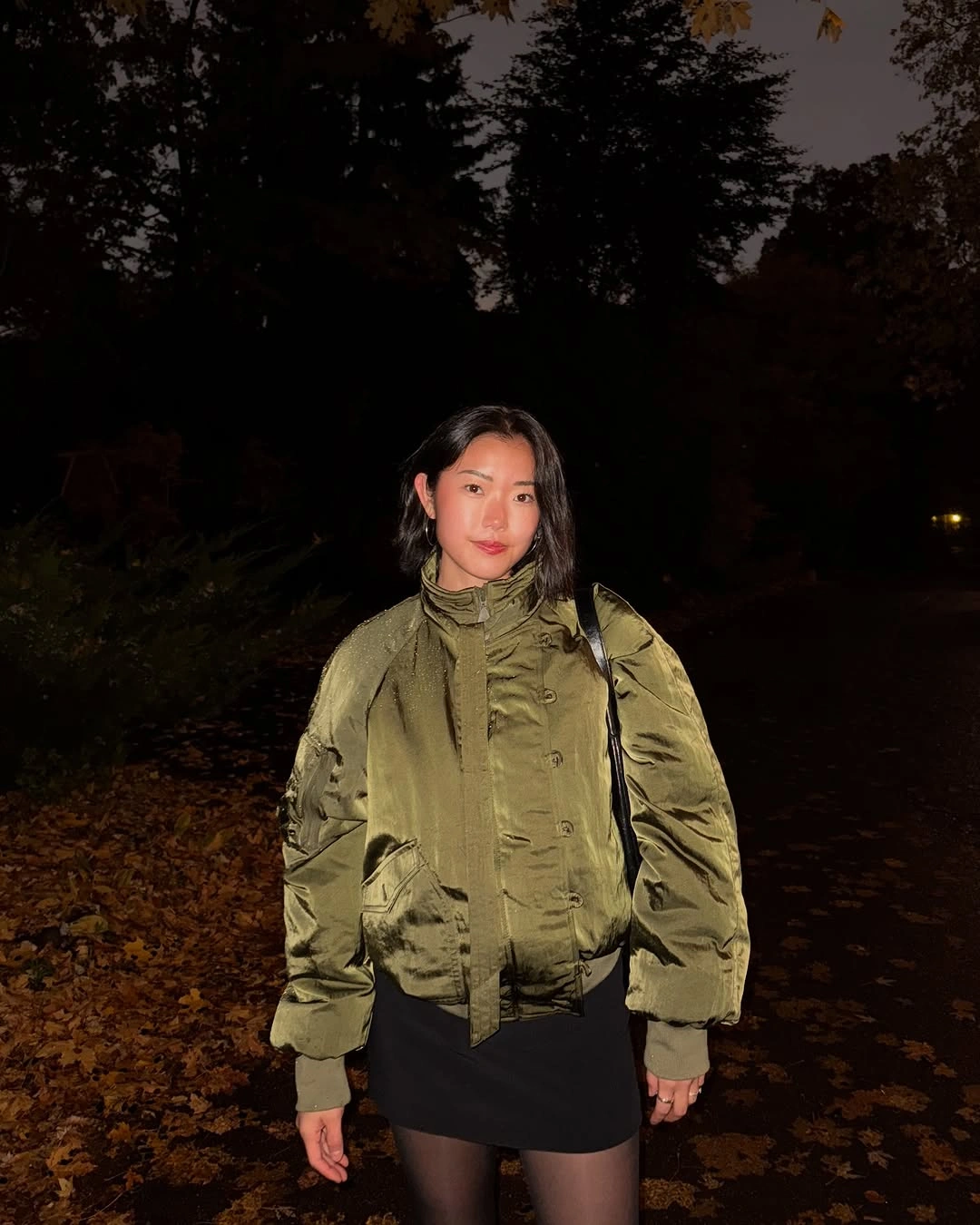 Olive bomber jacket over black mini skirt and dark tights