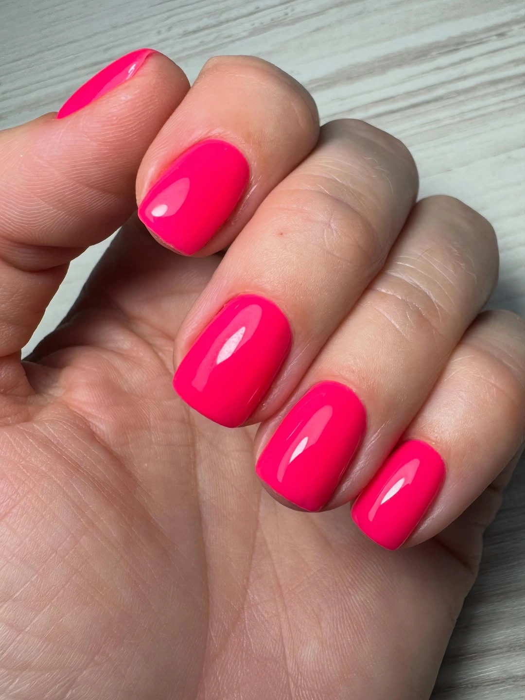 Short glossy hot pink square nails in a vivid solid color