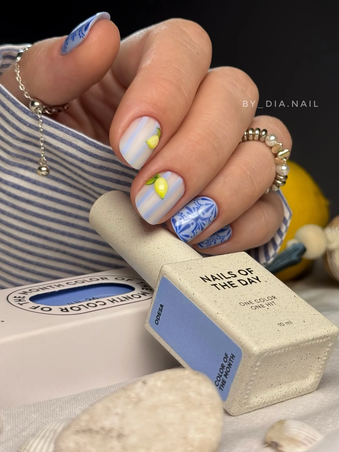 Short pale blue nails with blue lines and a yellow accent