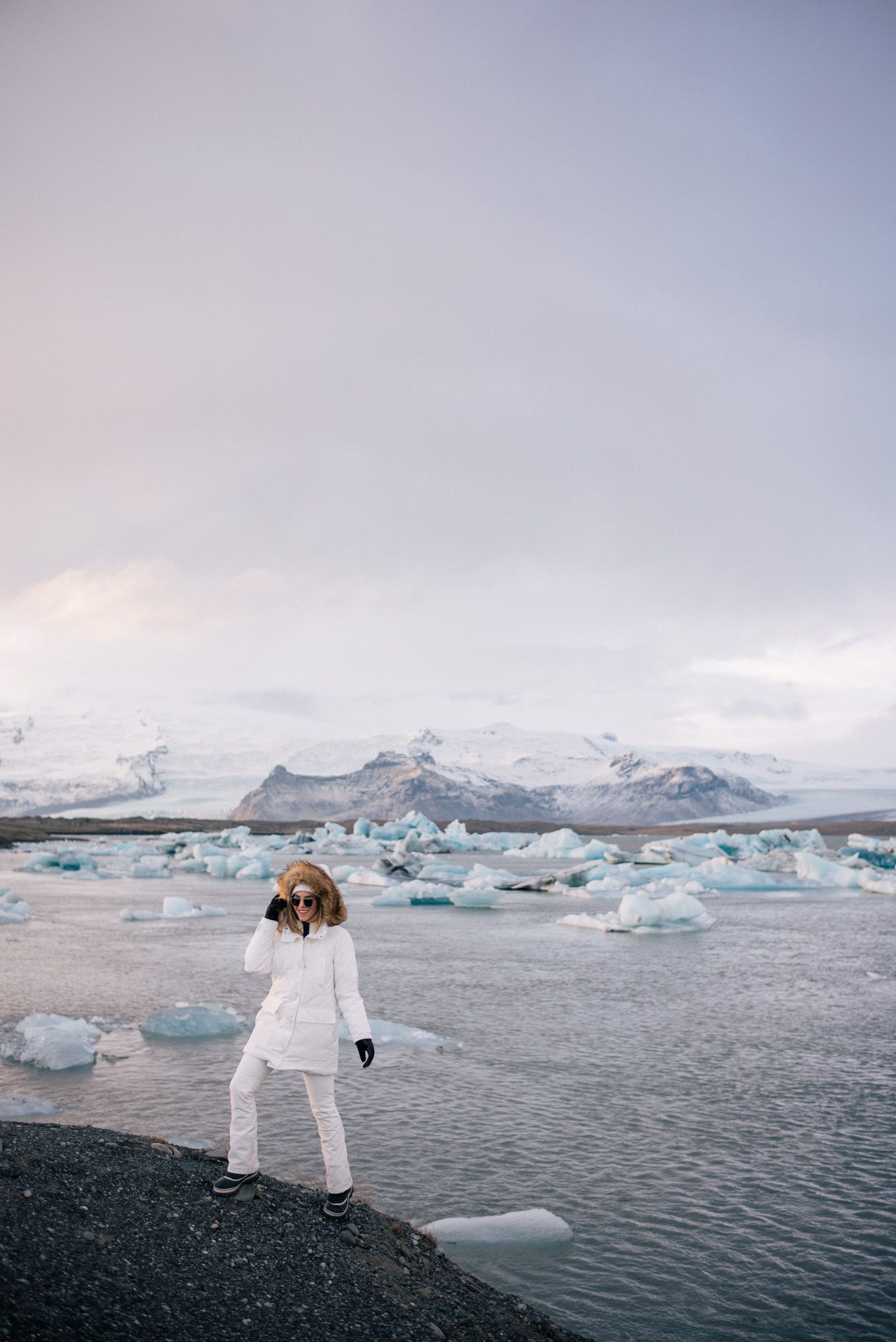 White Hooded Parka with Black Pants in a Glacial Landscape White Hooded Parka with Black Pants in a Glacial Landscape — Iceland Winter Outfits