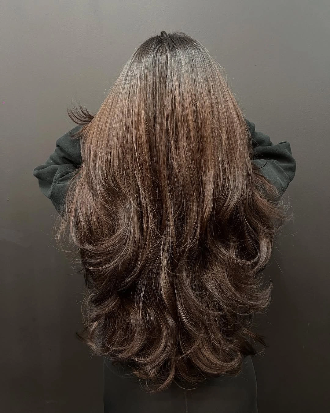 Back view of long brunette layered hair with flipped curled ends