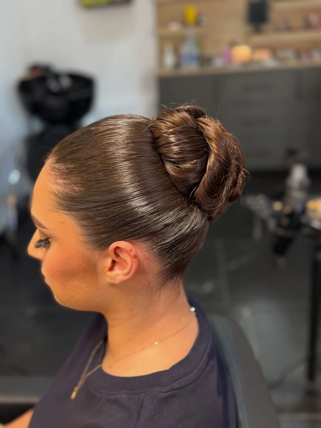 Sleek brown hair in high looped bun from side