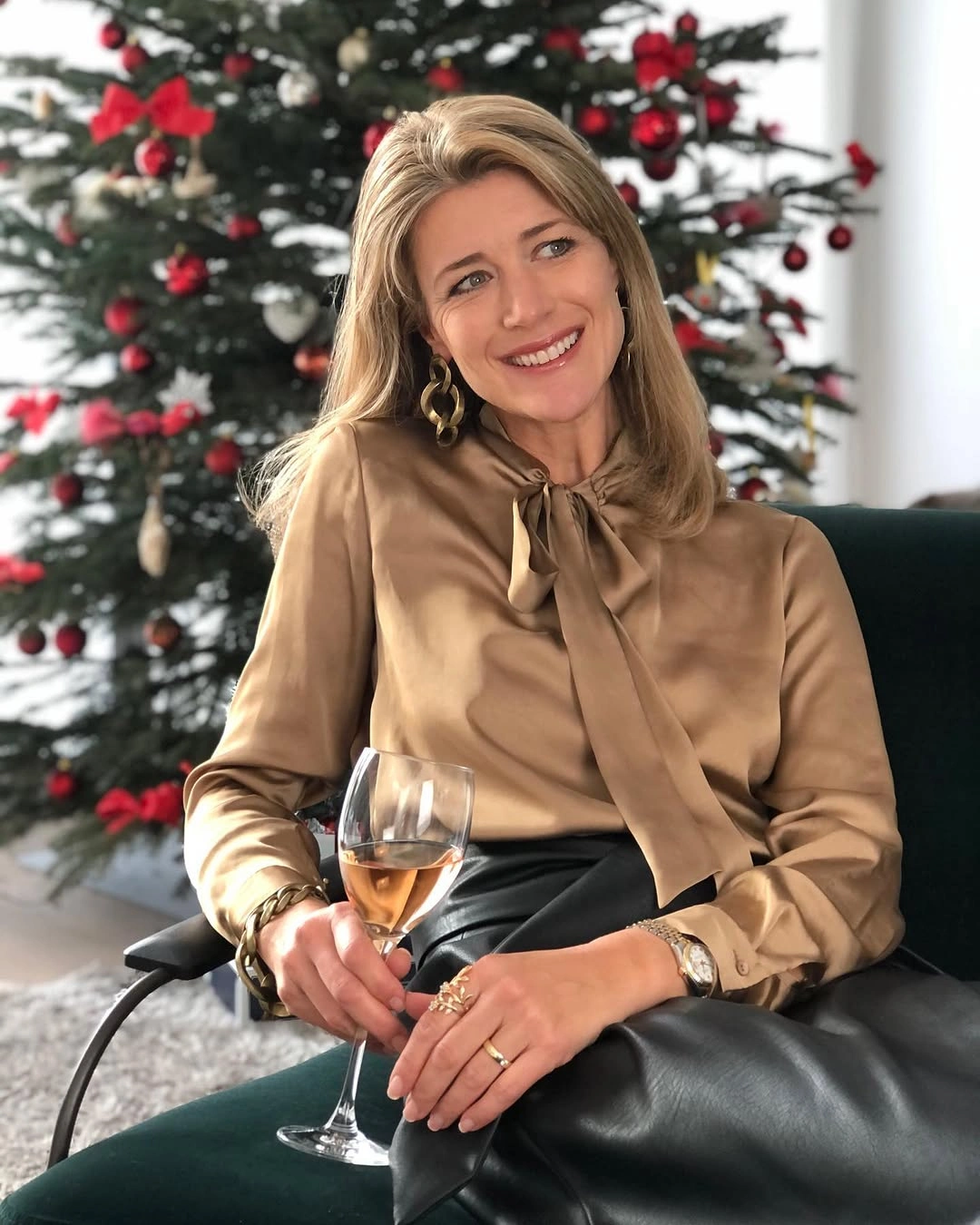Shiny-looking tan tie-neck blouse beside tree with red ornaments
