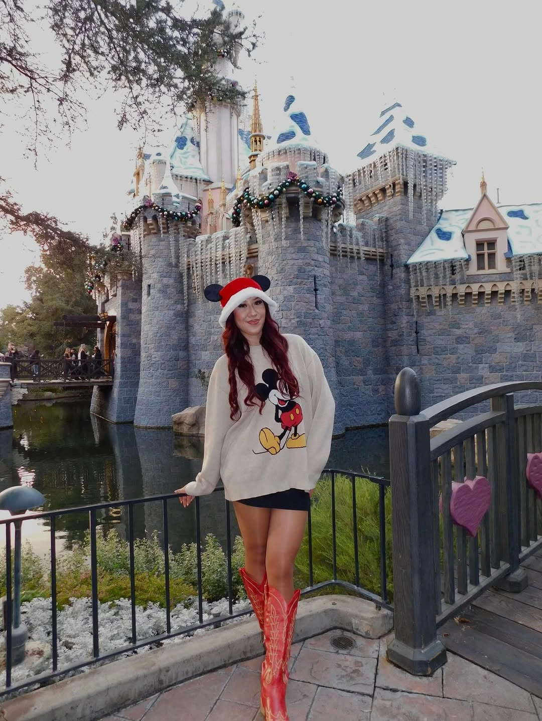 Cream graphic sweatshirt, Santa hat, and tall red boots
