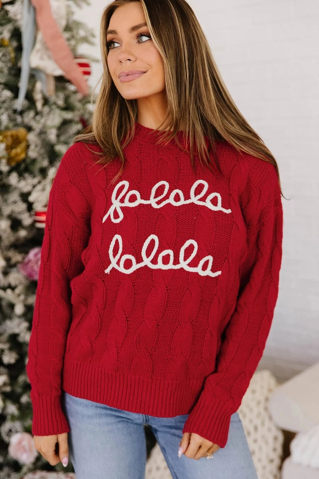 Red cable-textured sweater with white script and blue jeans