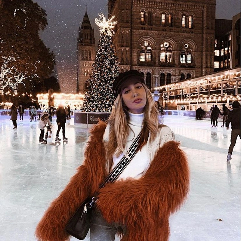 Rust fuzzy coat with white cap at outdoor ice rink