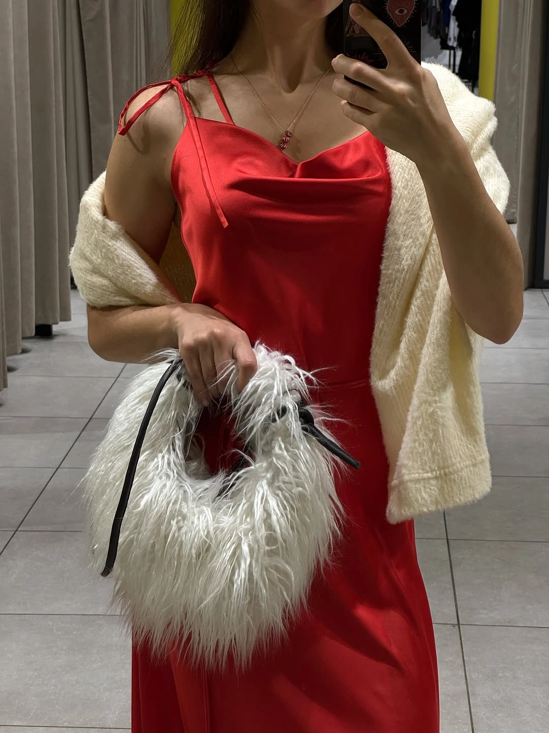 Red draped dress with pale wrap and fluffy white handbag