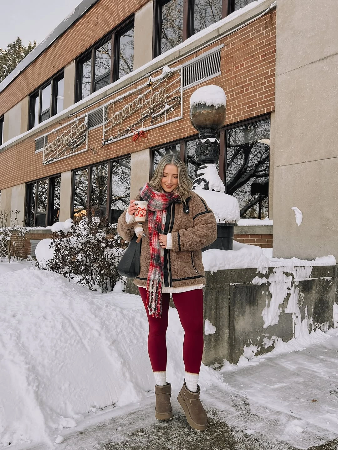 Brown jacket with plaid red scarf and burgundy leggings in snow